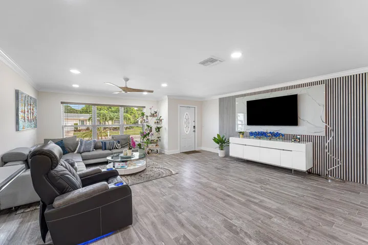 Spacious living area featuring wood-finish flooring, recessed lighting, and crown molding