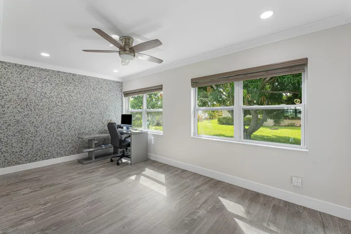 Spacious room featuring wood-finish flooring, a decorative accent wall, and recessed lighting