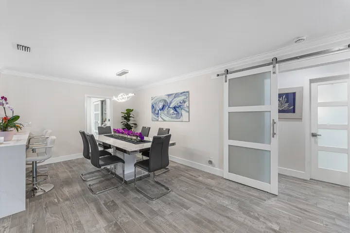 Spacious dining area featuring wood-finish flooring, crown molding, and a modern chandelier