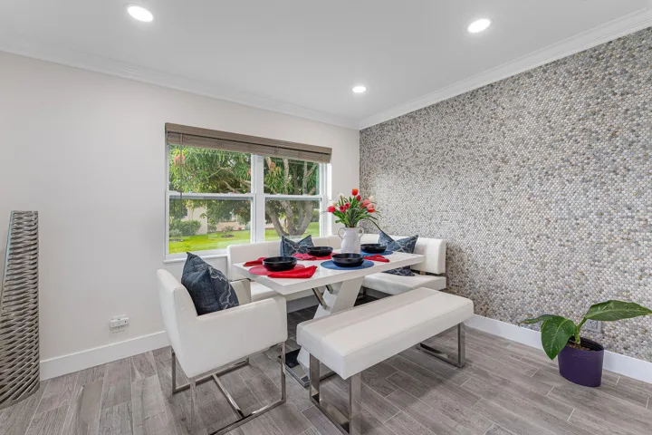 Dining space featuring a full-height mosaic tile accent wall, recessed lighting, and wood-finish flooring
