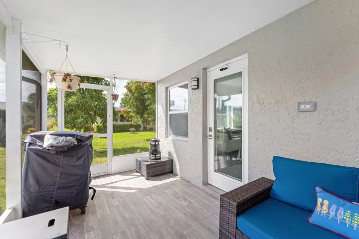 Screened-in patio with wood-finish flooring, textured exterior wall, exterior lighting fixtures, and a glass-paneled door