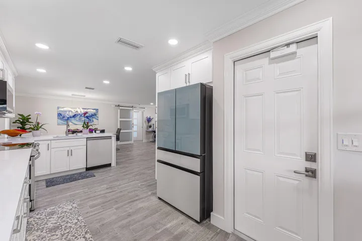 Bright kitchen featuring white cabinetry, light countertops, stainless steel appliances, wood-finish flooring, and recessed lighting