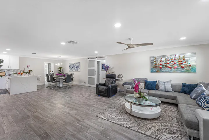 Open-concept living space featuring wood-look tile flooring, recessed lighting, and a modern ceiling fan