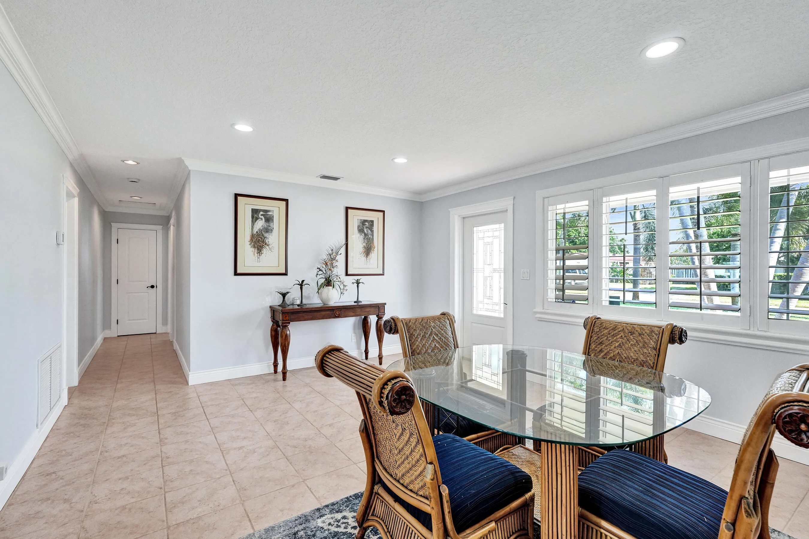This is the front entry to the home. The light-filled interior features tile flooring, white baseboards, and crown molding. The windows are insulated PGT and Norandex.