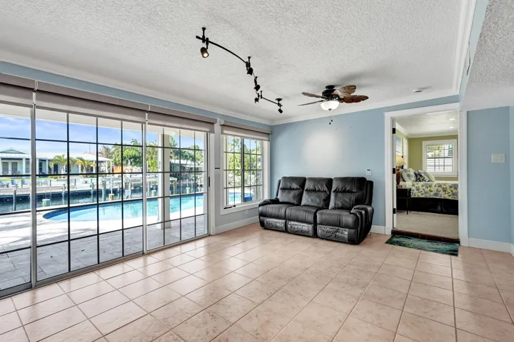 Spacious living area featuring large sliding glass doors, tile flooring, a ceiling fan, and track lighting