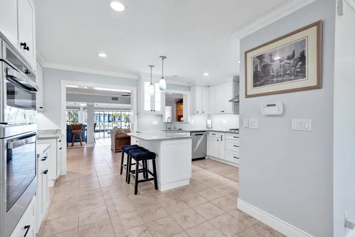 This exquisite chef's kitchen features beautiful white cabinetry, quartzite countertops, stainless steel appliances, a natural gas cooktop, wall oven & microwave, center island with pendant lighting and recessed ceiling lights, all done in 2024.