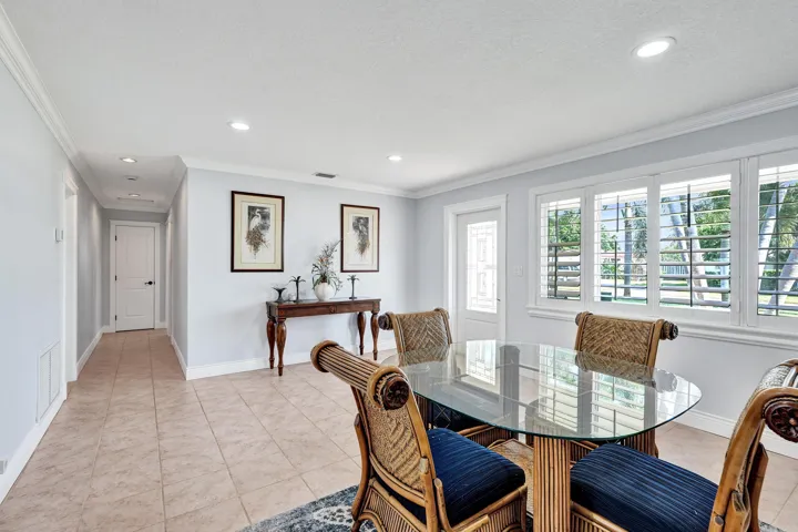 This is the front entry to the home. The light-filled interior features tile flooring, white baseboards, and crown molding. The windows are insulated PGT and Norandex.