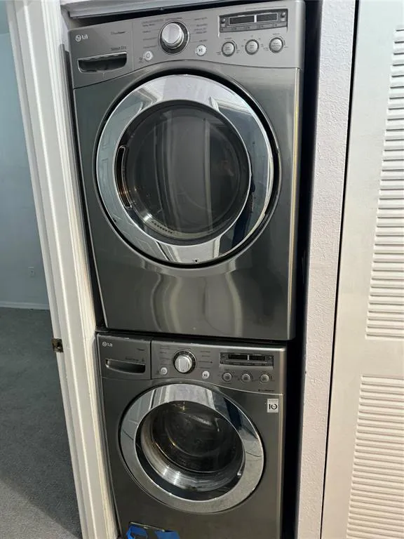 Stacked front-loading washer and dryer in a compact laundry area, featuring a dark metallic finish and chrome accents