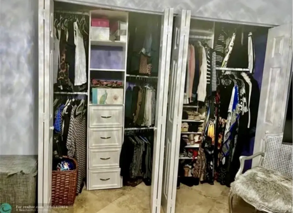 Bi-fold closet doors revealing a custom organization system with built-in shelving, drawers, and multiple hanging rods