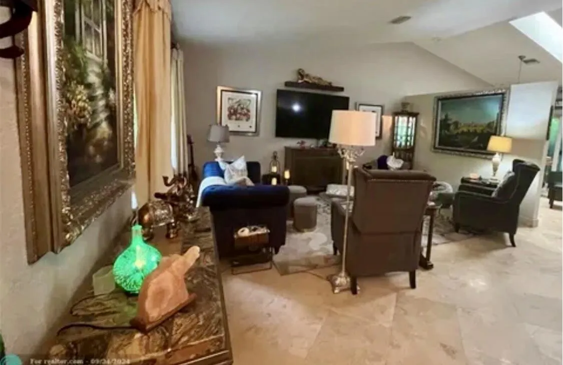 Spacious living area featuring sloped ceilings with recessed lighting, large format tile flooring, and a console table with a polished stone surface