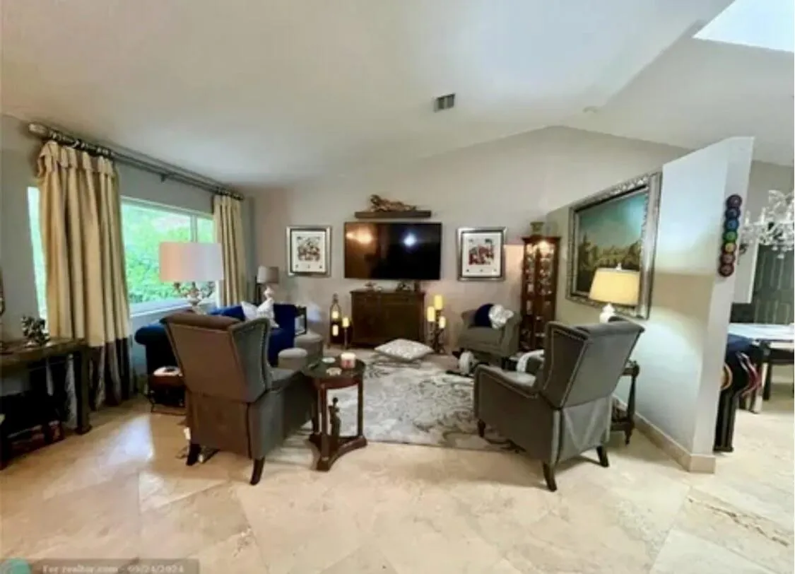 Expansive living area featuring vaulted ceilings, large picture windows, and light-toned tile flooring