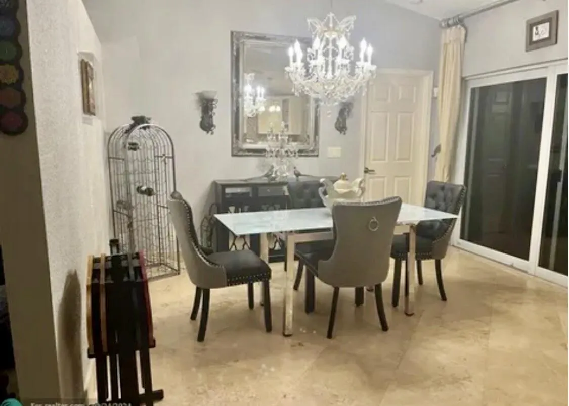 Dining area featuring a vaulted ceiling with a crystal chandelier, neutral wall tones, and light-toned tile flooring