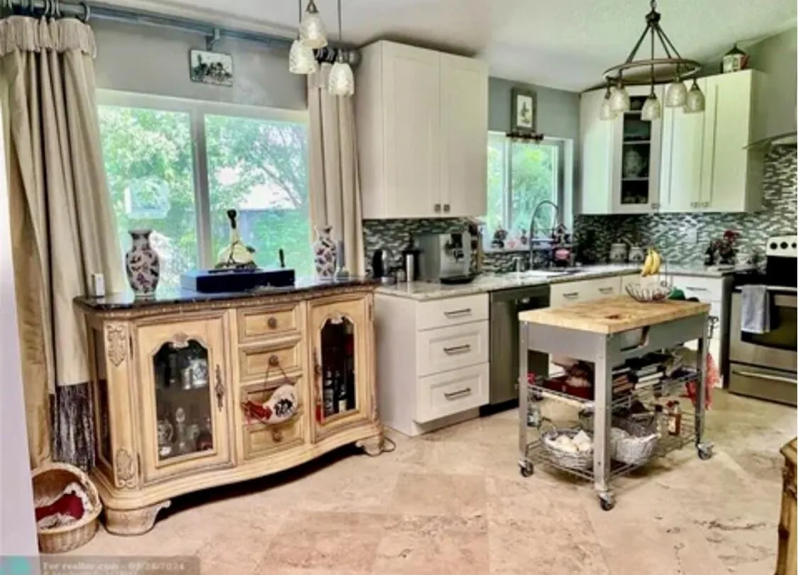 Well-appointed kitchen featuring light-toned cabinetry, a mosaic tile backsplash, and light-toned countertops