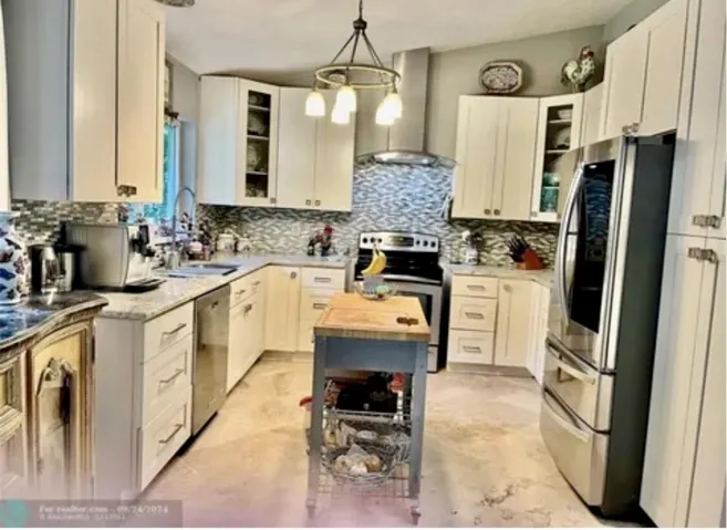 Kitchen featuring white cabinetry, light-toned countertops, stainless steel appliances, and a mosaic tile backsplash