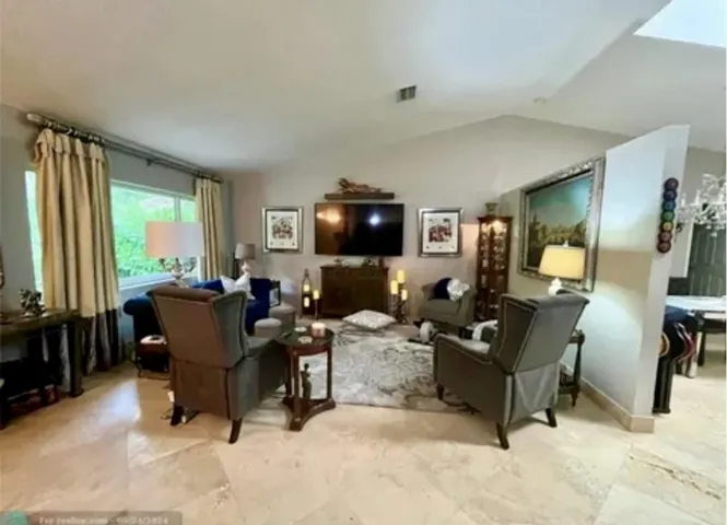 Expansive living area featuring vaulted ceilings, large picture windows, and light-toned tile flooring