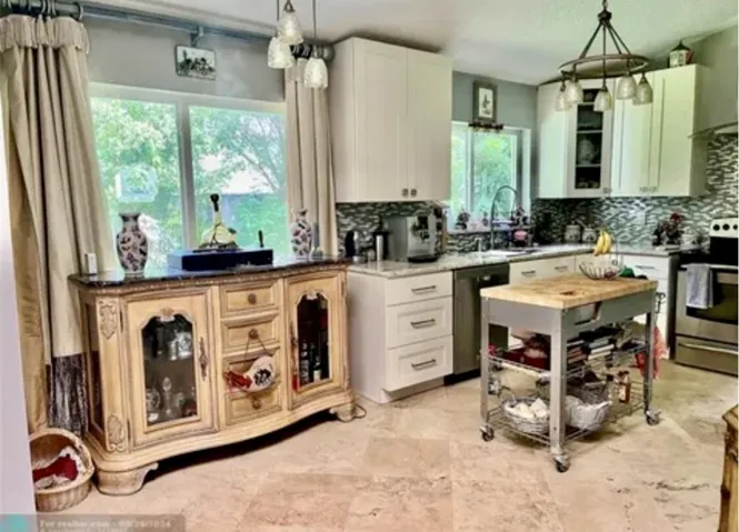 Well-appointed kitchen featuring light-toned cabinetry, a mosaic tile backsplash, and light-toned countertops
