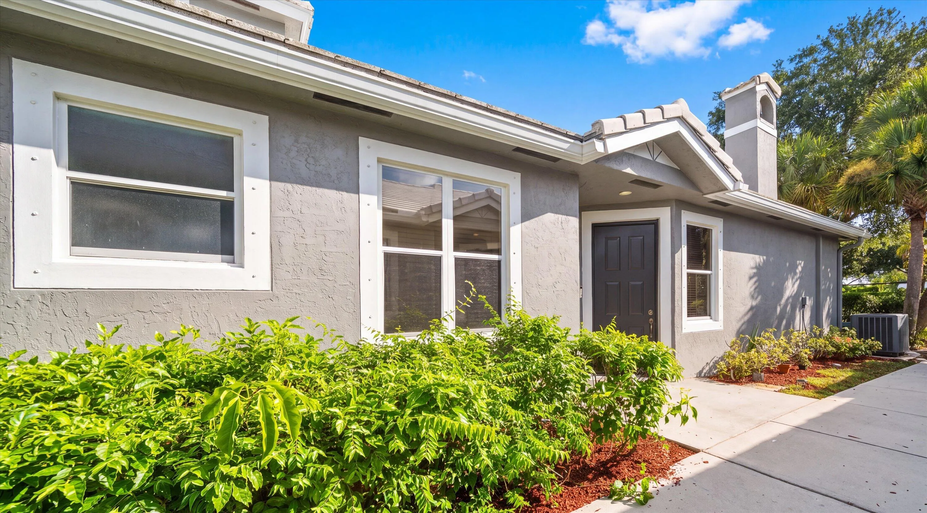 Stucco exterior featuring a tiled roof, white trim windows, a prominent entry door, and a decorative chimney