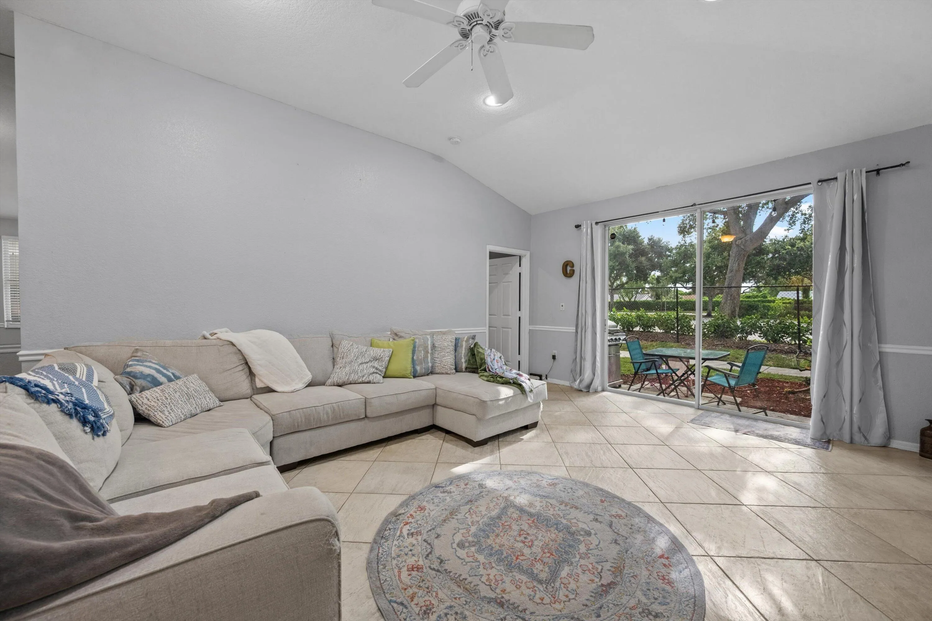 Spacious living area featuring vaulted ceilings, tile flooring, and a ceiling fan with integrated lighting