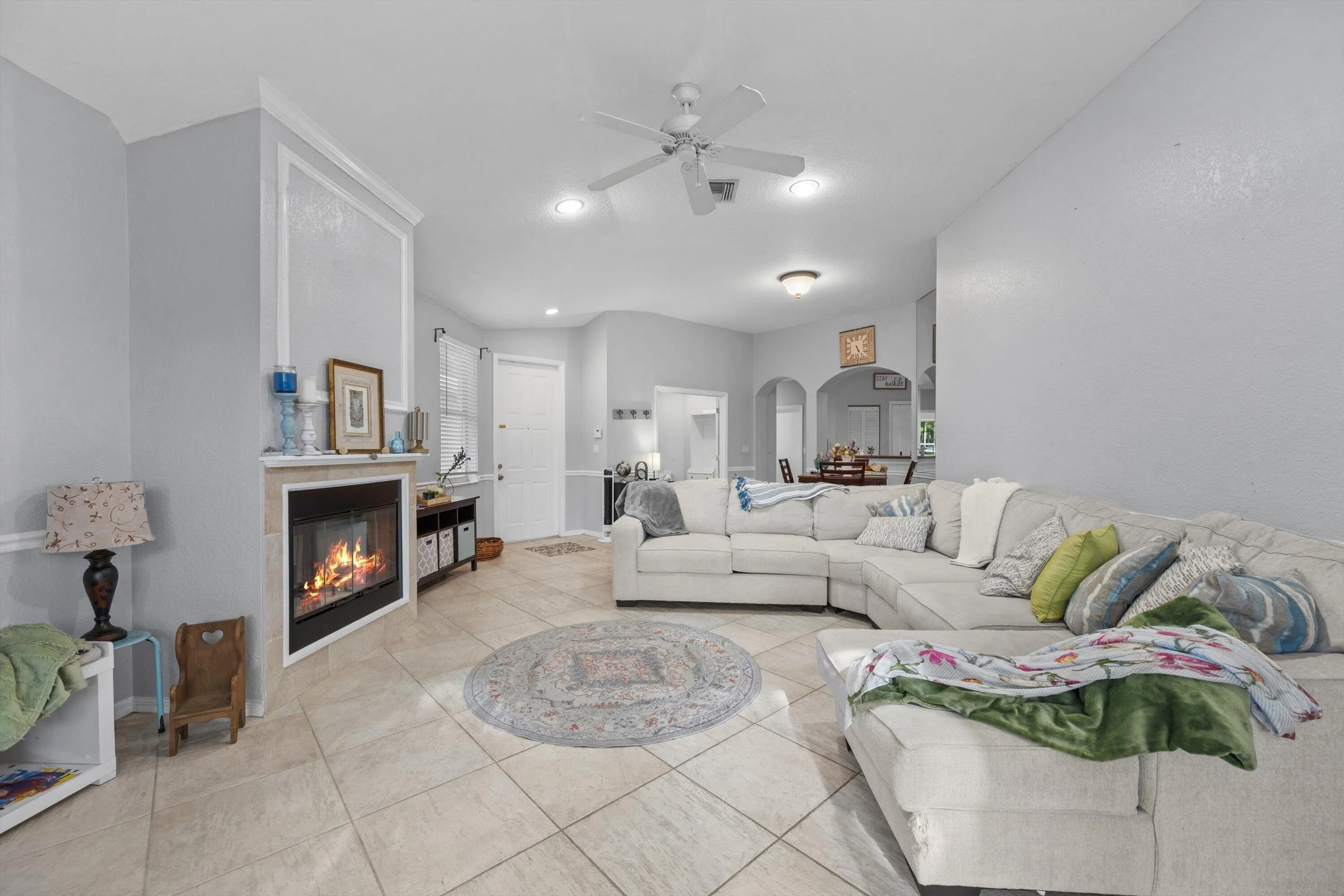 Living area featuring a corner fireplace with a mantel, tile flooring, recessed lighting, and a ceiling fan