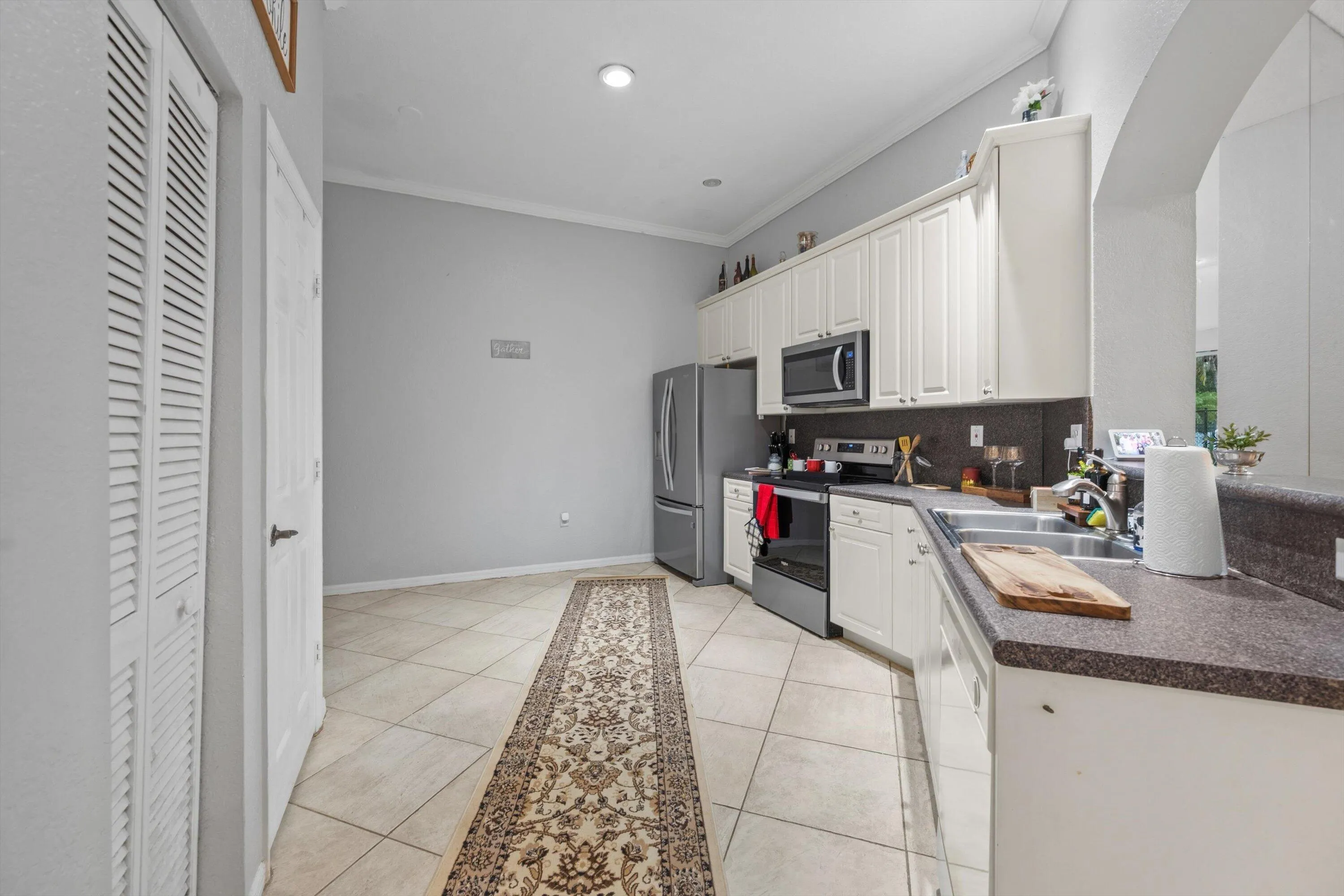 Kitchen featuring white cabinetry, stainless steel appliances, dark countertops, tile flooring, and recessed lighting