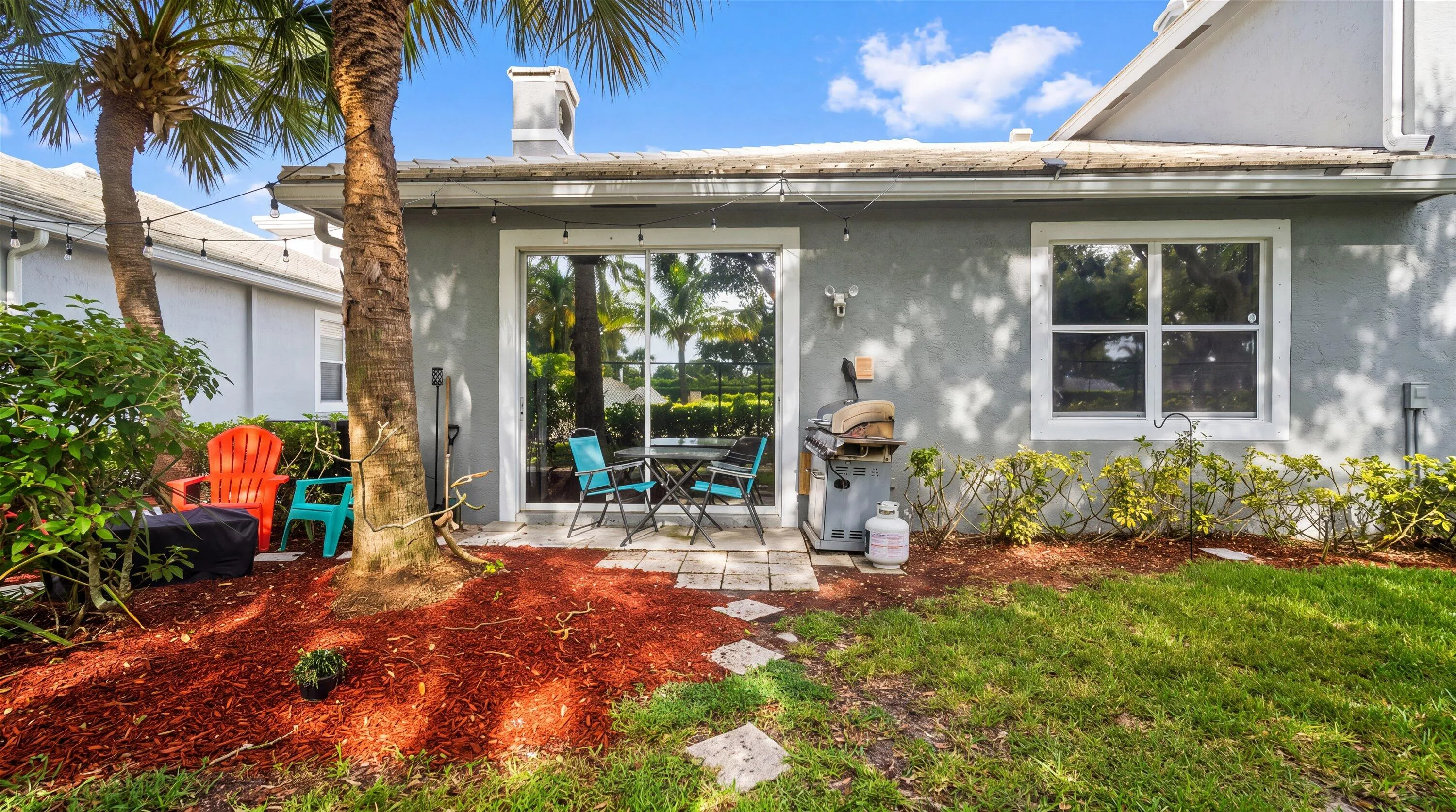Patio area featuring a sliding glass door, a window with white trim, and a stepped stone pathway