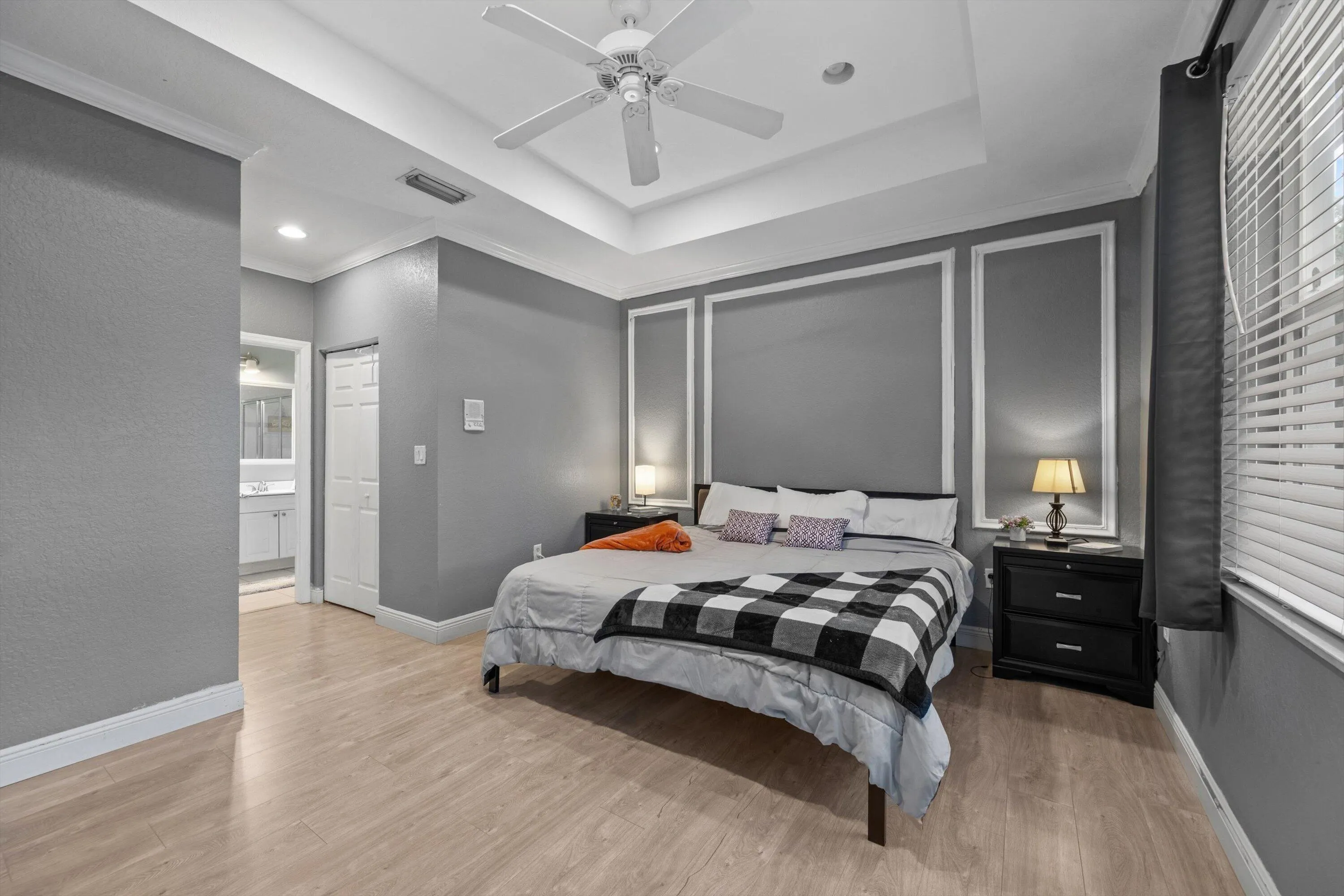 Tray ceiling with a ceiling fan, light wood-finish flooring, and crown molding