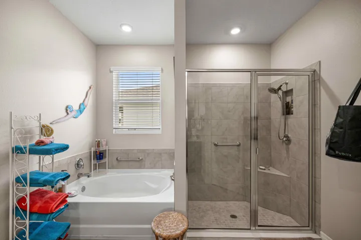 Bathroom featuring a built-in soaking tub with tiled surround, a walk-in shower with glass enclosure, tiled walls, and a built-in shower bench