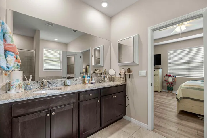 Bathroom featuring a double vanity with dark wood cabinetry, light speckled countertop, and dual integrated sinks