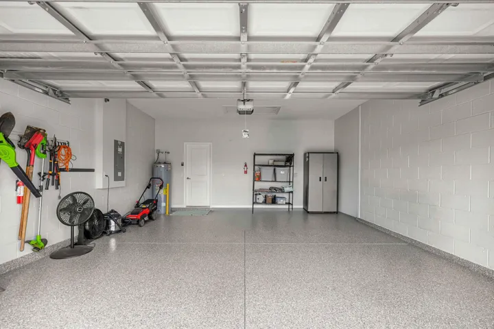 Spacious garage featuring a durable epoxy-coated floor, painted block walls, and an insulated garage door