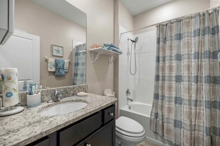 Bathroom featuring a vanity with a light-toned stone countertop, undermount sink, and dark cabinetry