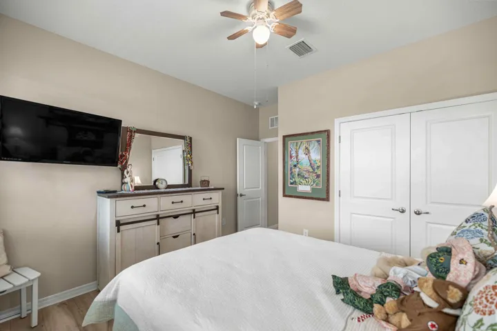 Neutral tone walls with light wood-finish flooring, featuring a ceiling fan with integrated lighting