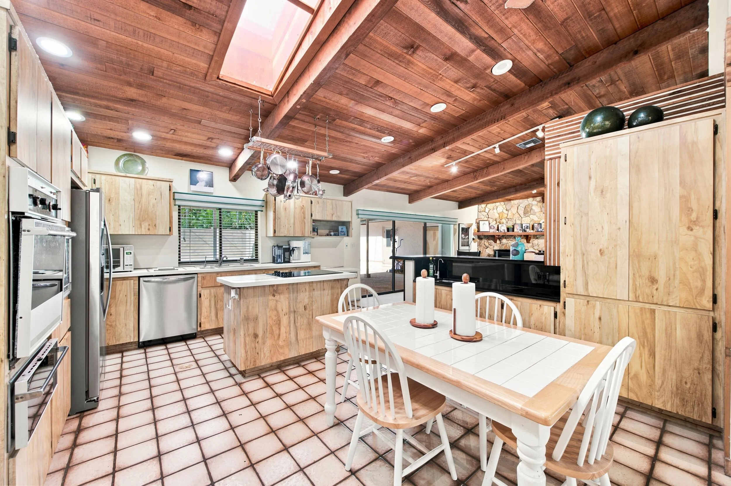 Kitchen featuring a vaulted wood-paneled ceiling with exposed beams, skylight, recessed lighting, and tile flooring