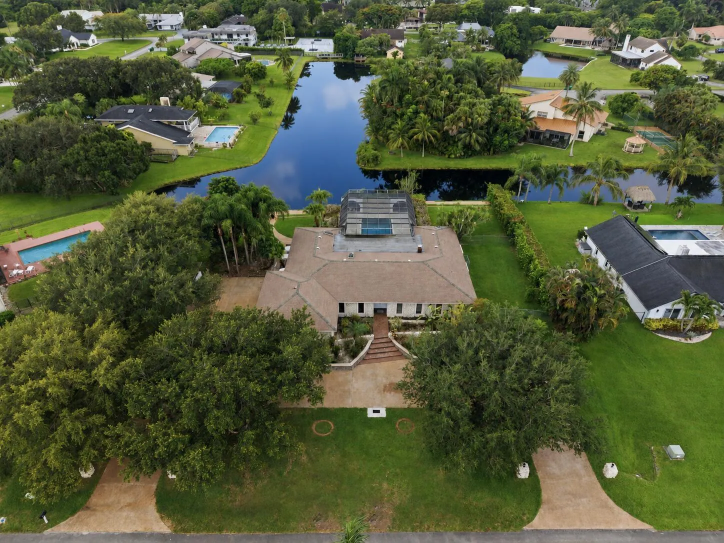 Expansive property featuring a large residence with a multi-level roofline, a private pool, and mature trees