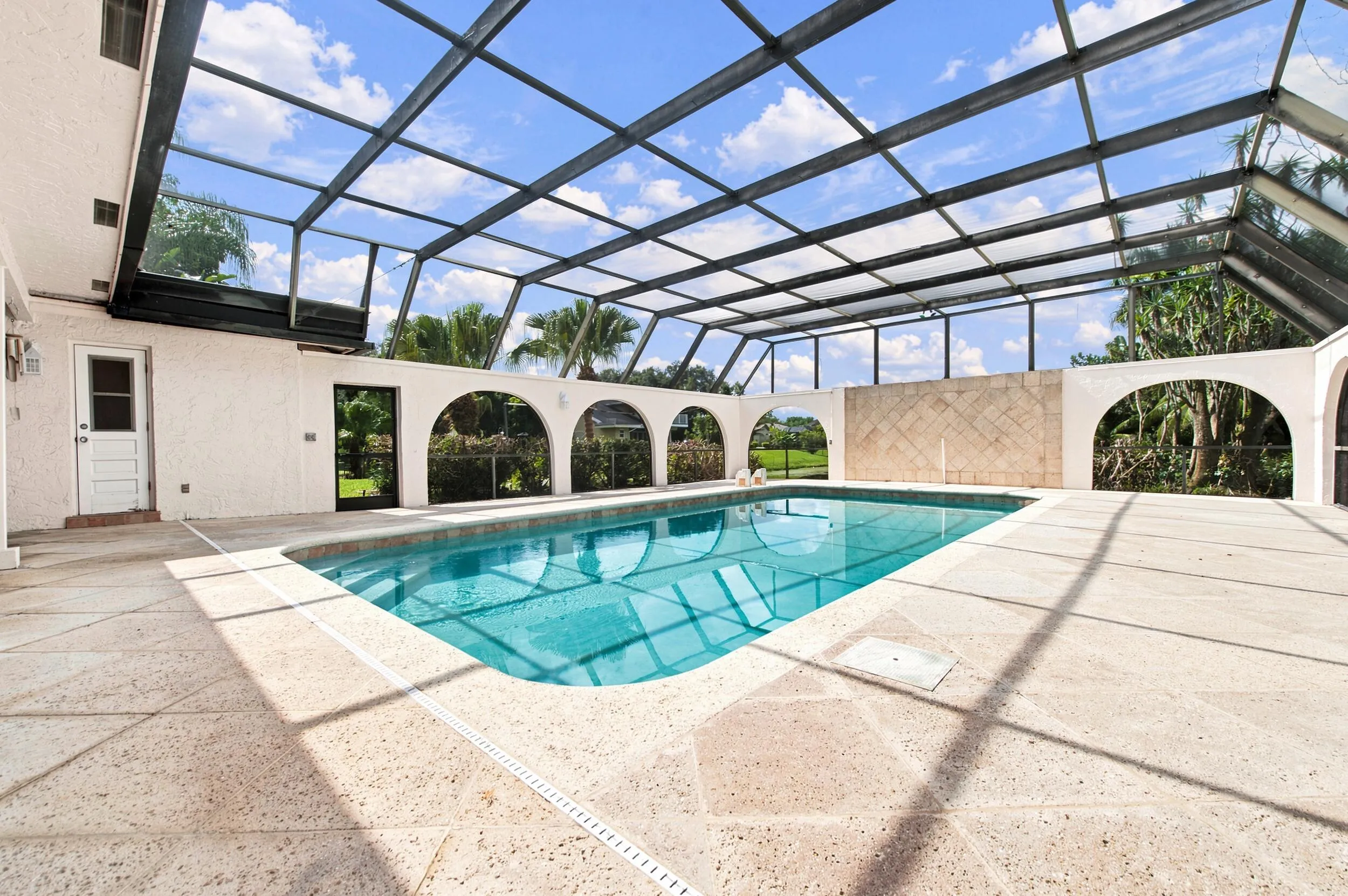 Screened-in pool enclosure featuring a rectangular swimming pool with integrated steps