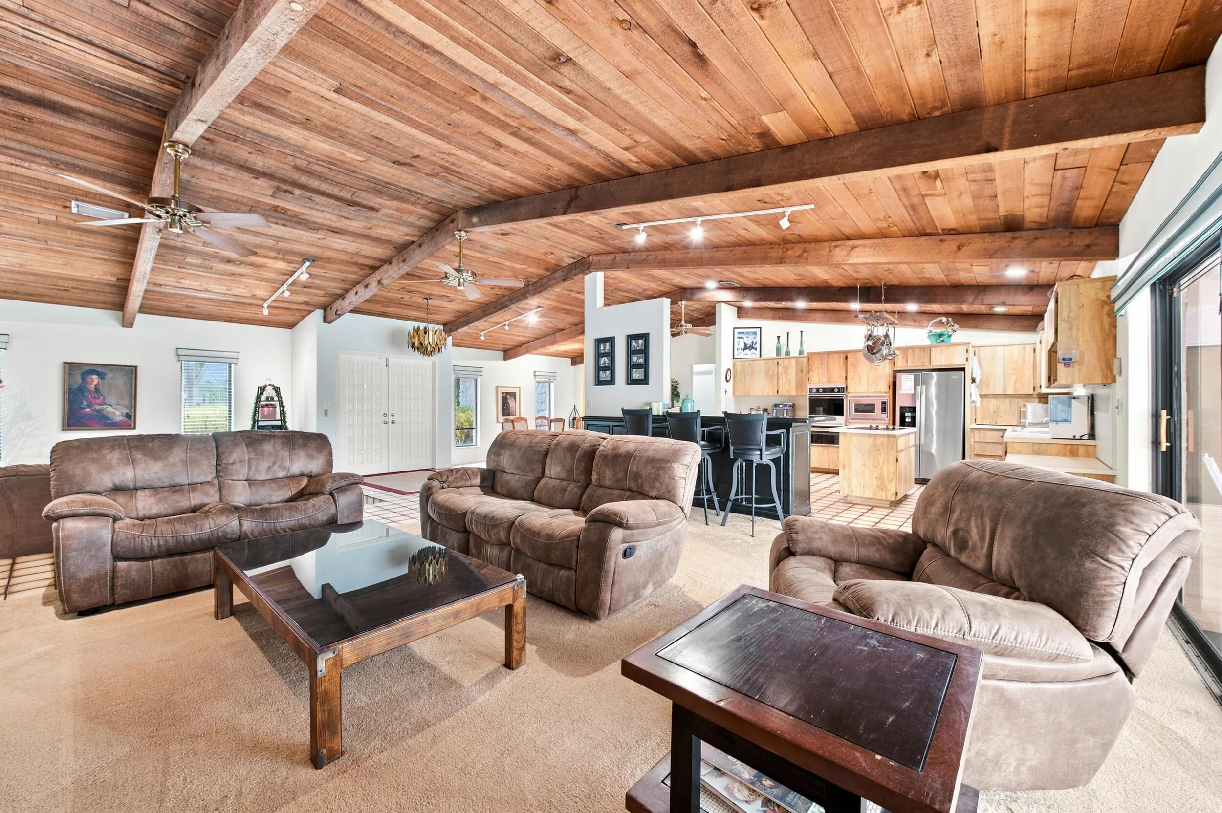 Vaulted wood-planked ceilings with exposed beams, recessed lighting, and ceiling fans