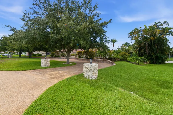 Expansive green lawn with mature trees and a curving aggregate driveway