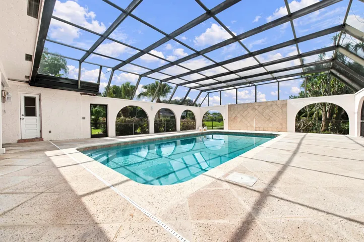 Screened-in pool enclosure featuring a rectangular swimming pool with integrated steps