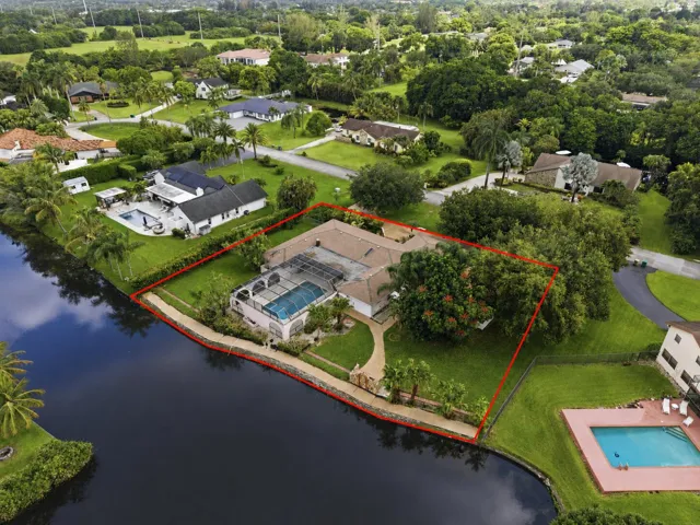 Waterfront property featuring a screened-in swimming pool and a well-maintained lawn