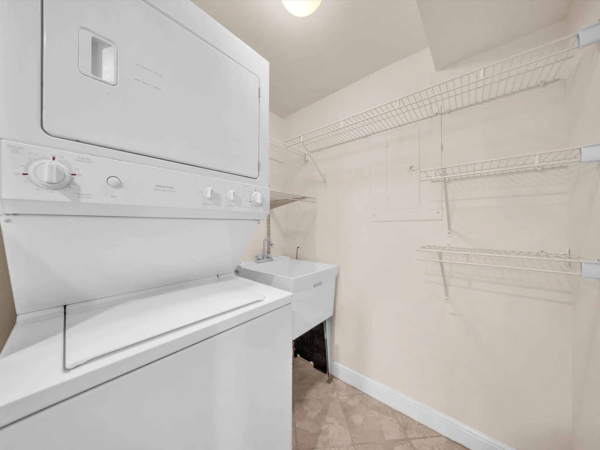 Interior laundry room with stacked washer dryer and sink