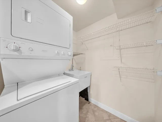 Interior laundry room with stacked washer dryer and sink