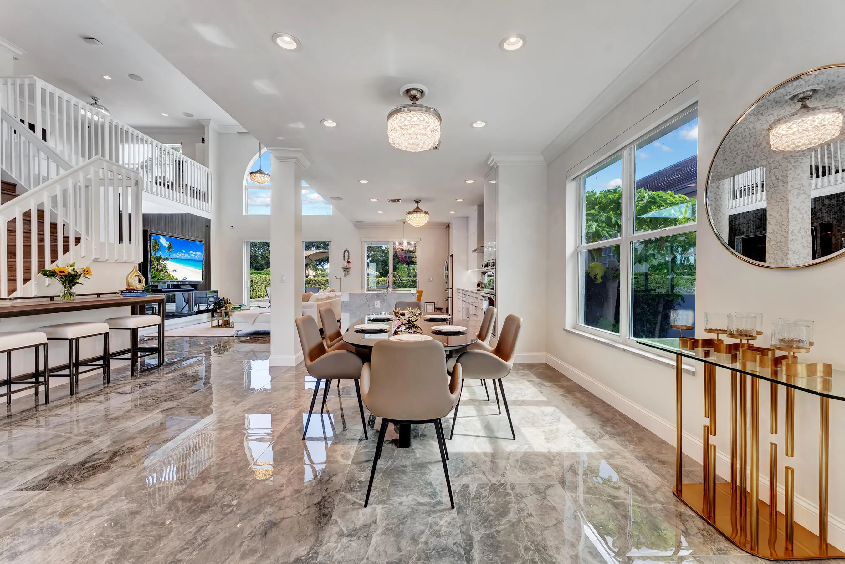 Dining space framed by the sweeping staircase and two-story ceiling with statement lighting.