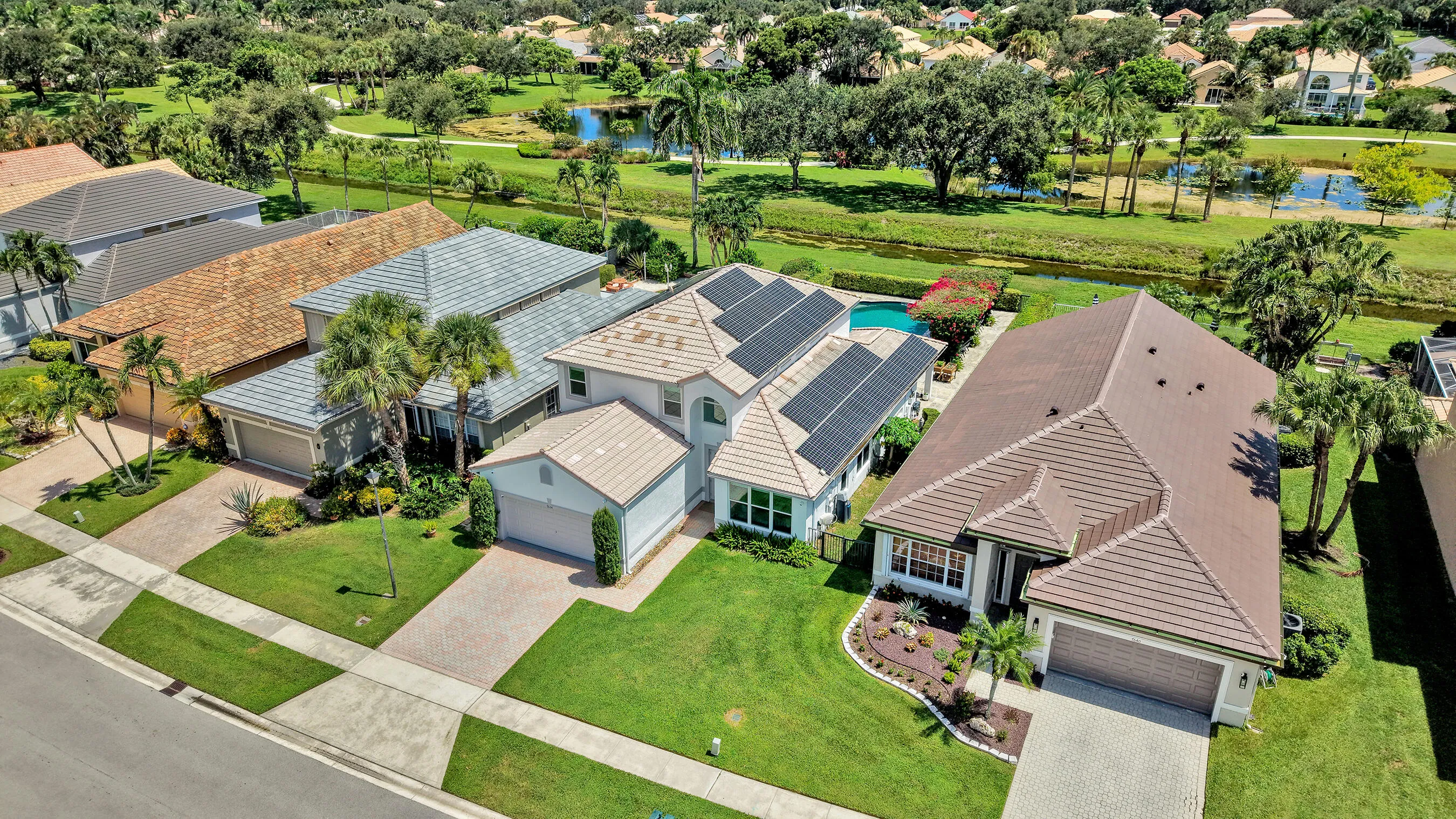 Angled aerial showing the tile roof, solar panel array, pool, and landscaped lot.
