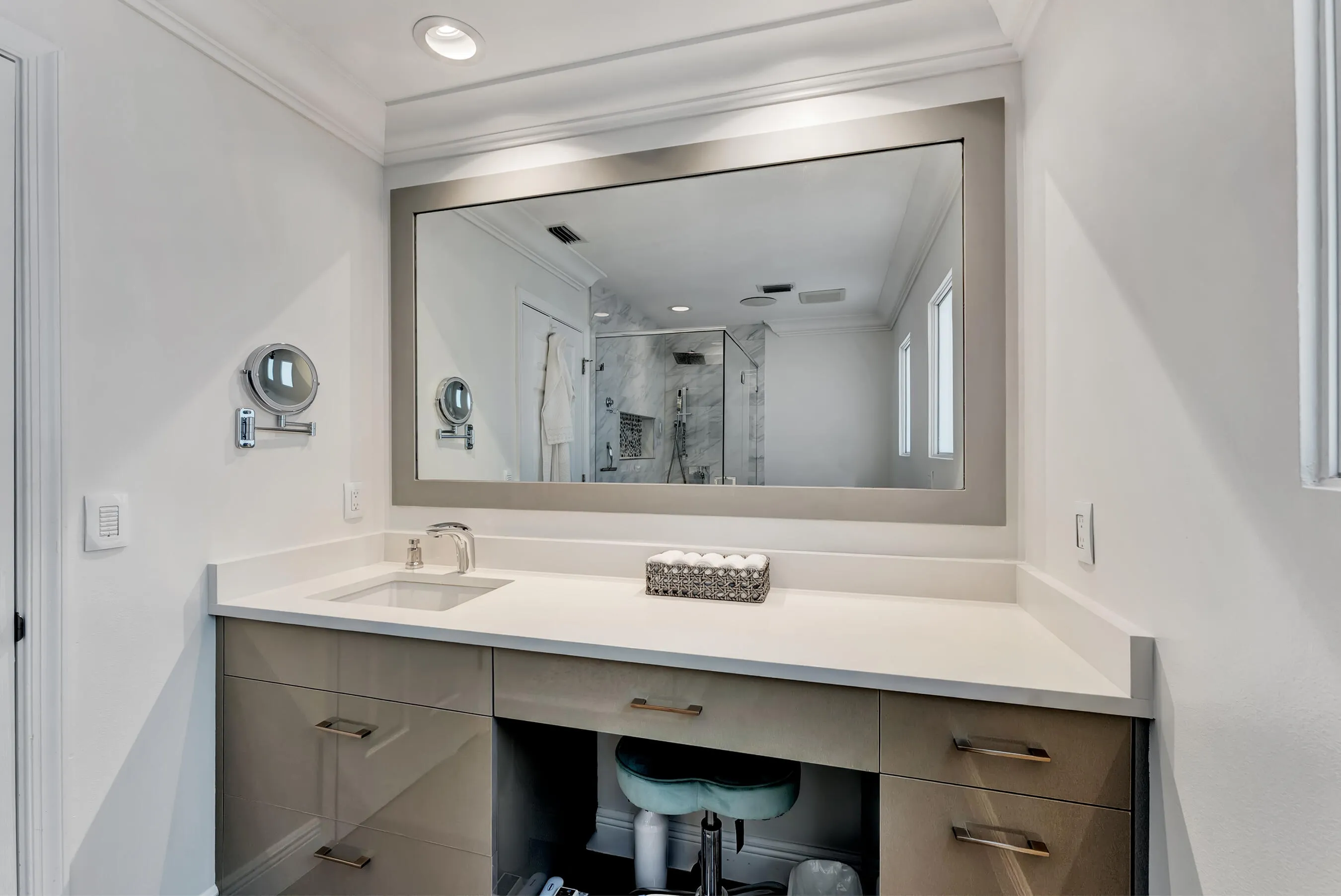 Upstairs bathroom with extended quartz-top vanity, seated station, and oversized mirror.