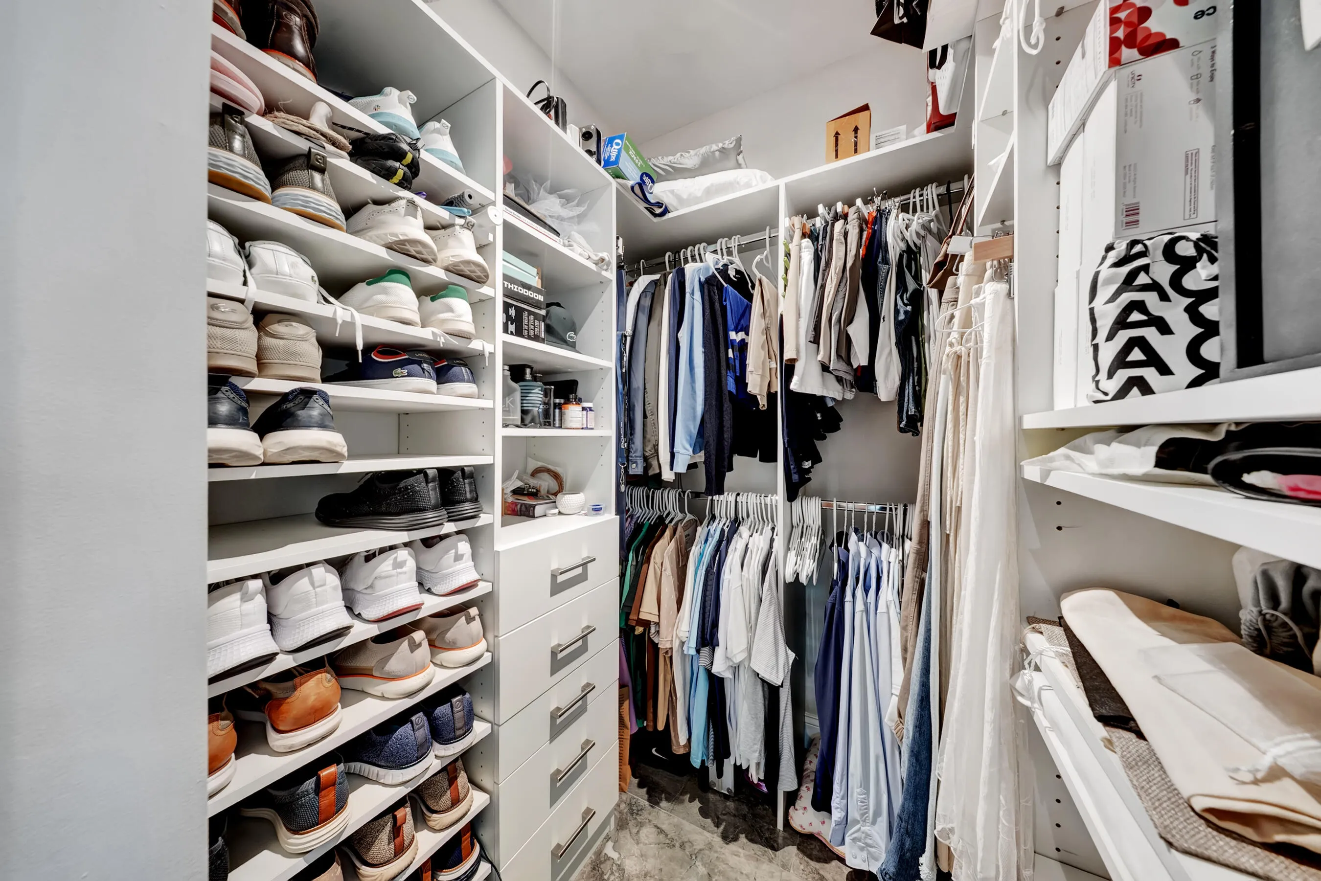 Custom walk-in closet with built-in shelving, drawer banks, and shoe display storage.
