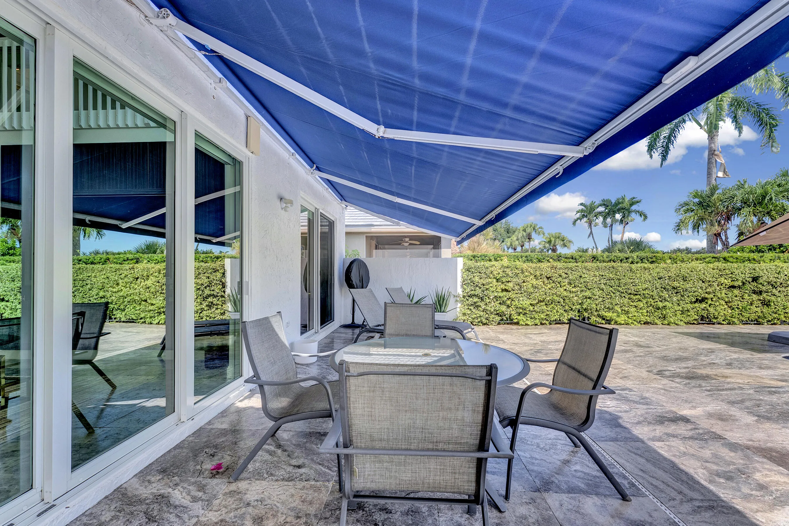 Shaded outdoor dining area beneath a retractable awning, just off the main living area sliders.