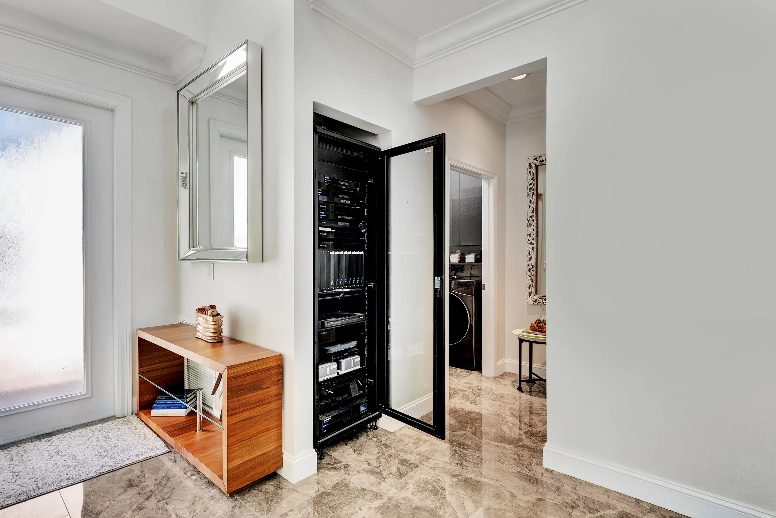 Entry hall featuring a built-in smart-home AV rack closet with laundry room beyond.