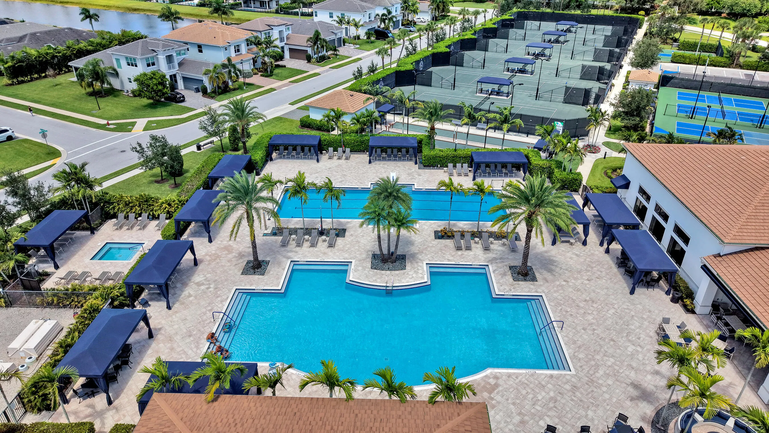 Resort-style community pool with lap lanes, spa, palm-lined sundeck, and shaded cabana seating.