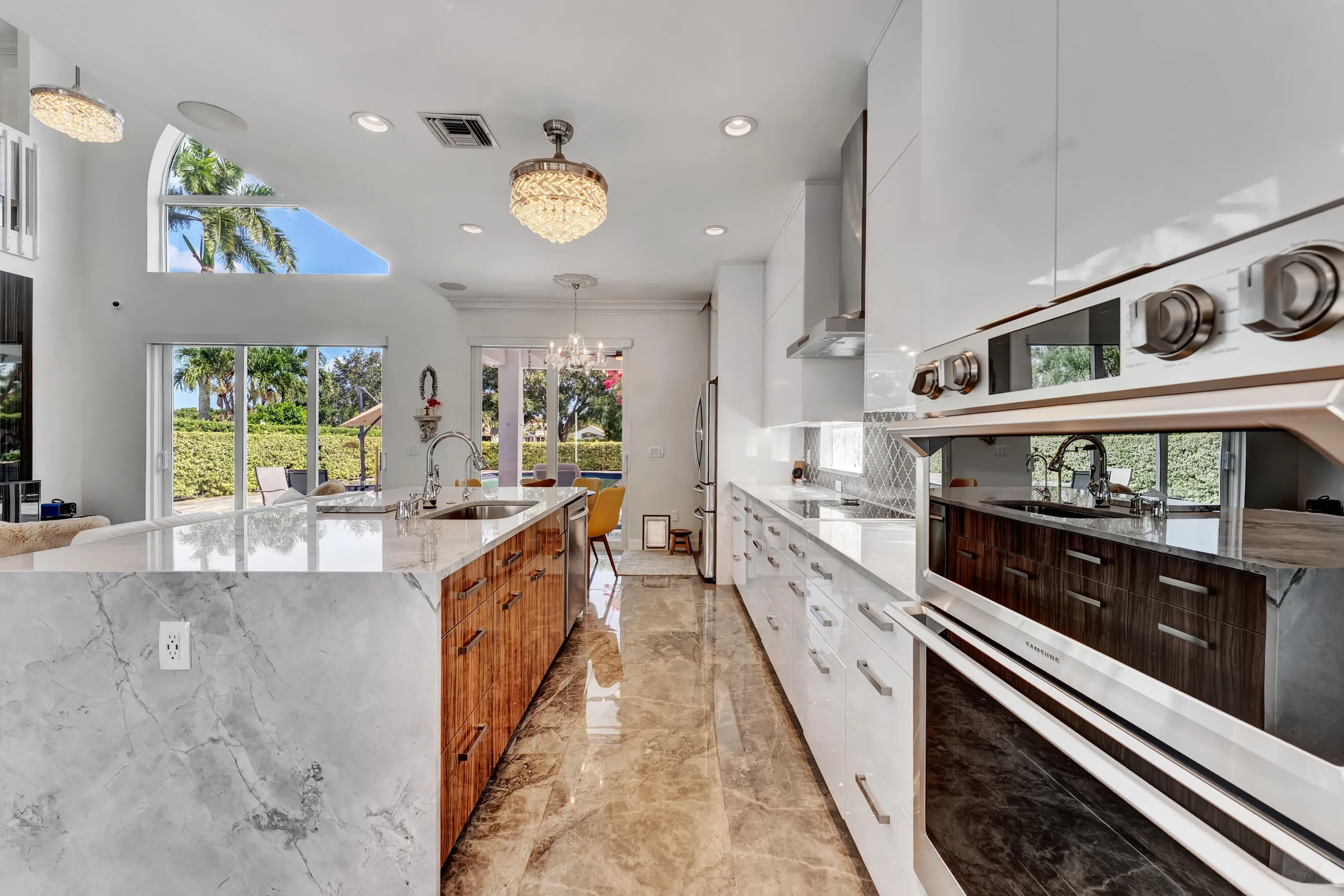 Kitchen with stainless steel appliances, designer range hood, arabesque tile backsplash, and abundant custom cabinetry.