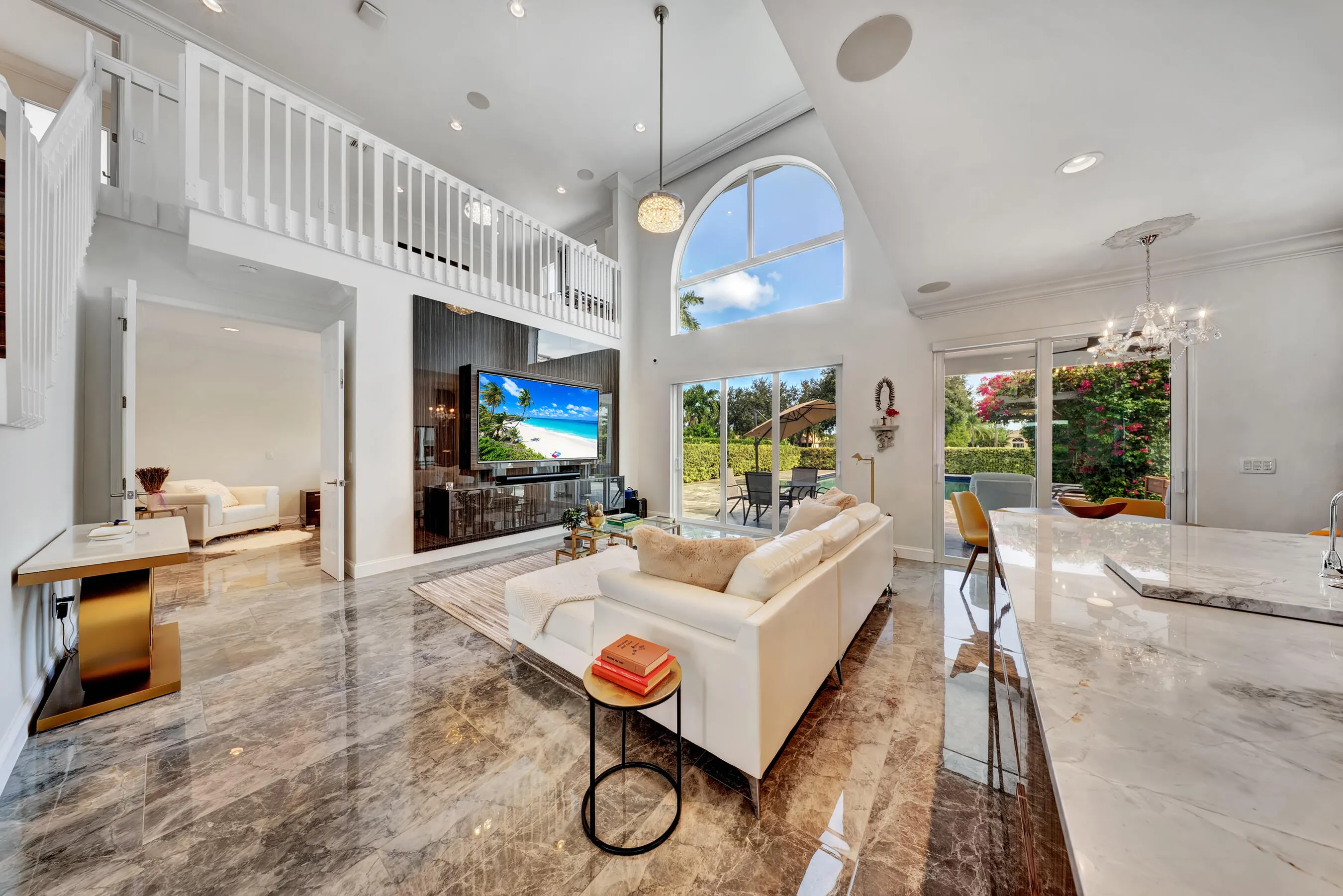 Two-story great room with loft overlook, entertainment wall, and sliding glass doors opening to the pool and patio.