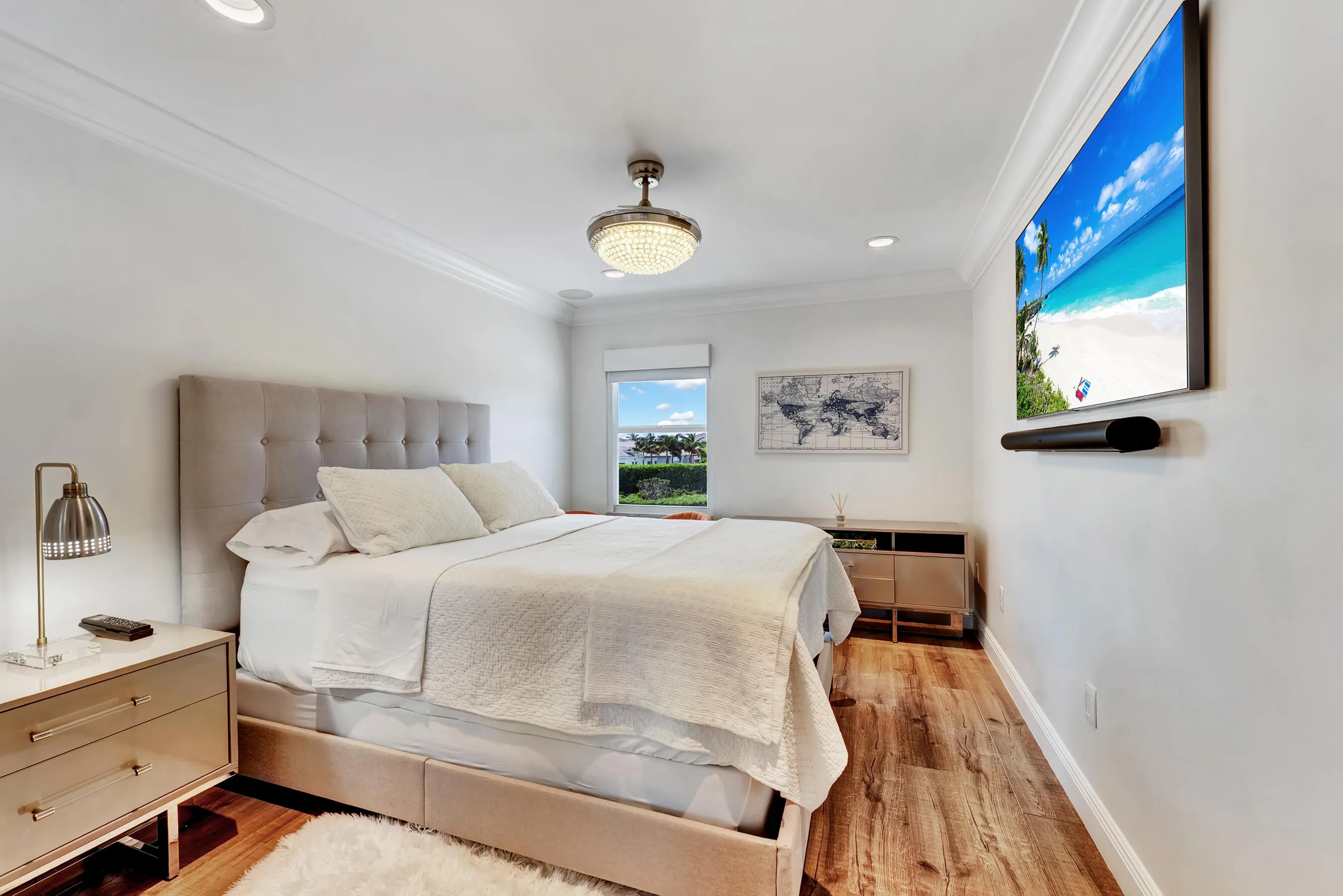 Guest bedroom with upholstered bed, garden views, and designer ceiling fixture.